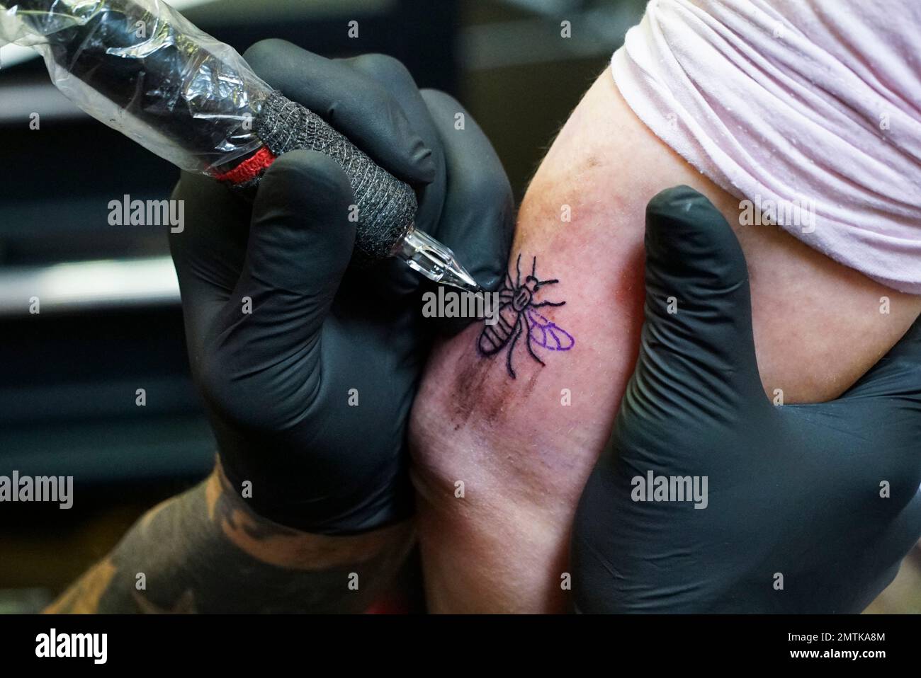 A tattoo artist tattoos a bee on a person's arm at his studio in Manchester, Sunday, May 28, 2017. The city's tattoo artists are offering a tattoo of a worker bee with A tattoo artist tattoos a bee on a person's arm at his studio in Manchester, Sunday, May 28, 2017. The city's tattoo artists are offering a tattoo of a worker bee with