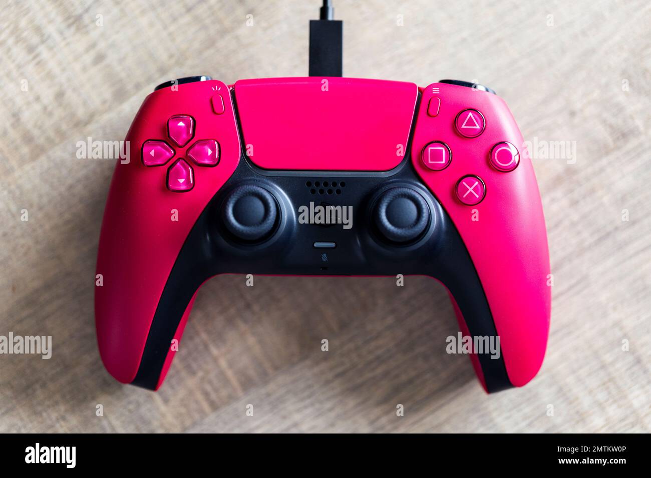 Brecht, Belgium - 26 januari 2023: A top down portrait of a sony playstation  5 cosmic red wireless controller lying on a wooden table with the usb-c c  Stock Photo - Alamy