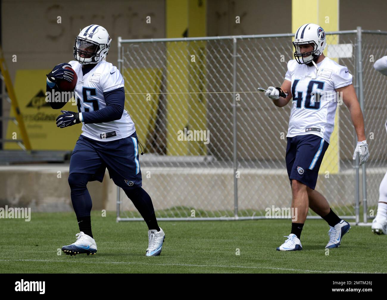 Tennessee Titans fullback Jalston Fowler 45 runs a drill with a football attached to a string held by Joe Bacci 46 during the team s organized team activity at its NFL football training