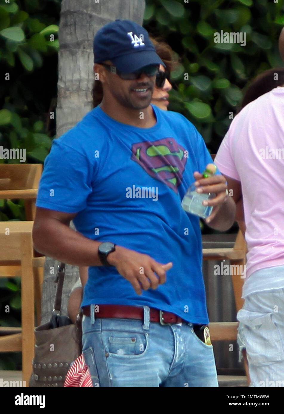 Actor Shemar Moore wears a Superman t shirt during a stroll on the beach.  Moore carried along a bottle of spray tanning oil in his pocket and had  what looked to be