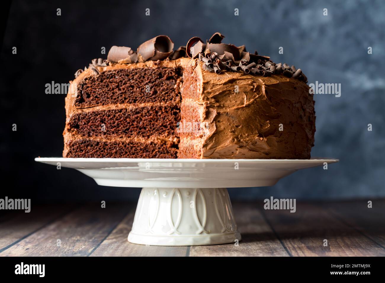 A delicious homemade triple layered low sugar chocolate cake on a pedestal stand Stock Photo