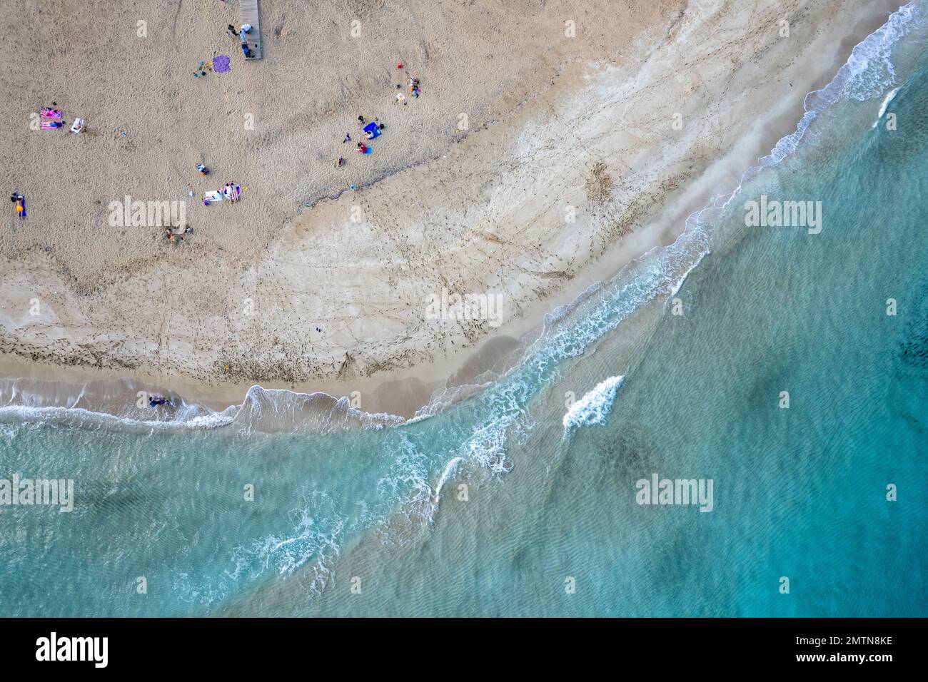 Drone aerial of people relaxing in a sandy beach in winter. Fog tree bay beach, holiday resort Protaras Cyprus. Stock Photo