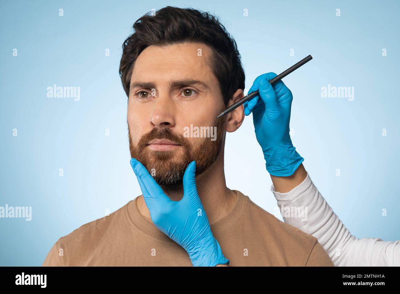 Aesthetic cosmetology concept. Man getting pencil marks on face skin