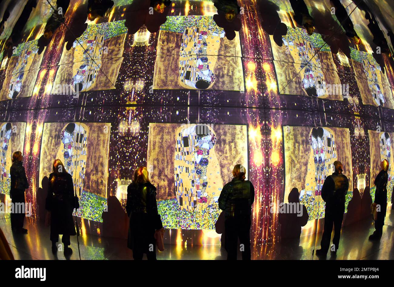 29 January 2023, Saxony, Leipzig: In the Kunstkraftwerk, a former combined heat and power plant, visitors stand in a hall of mirrors, in which the famous painting 'Kiss' is also reflected several times. The mirrored room is part of the multimedia installation 'Gustav Klimt - GoldExperience', in which many famous paintings are projected in the room. In the show by Italian Stefano Fake and his Fake Factory, the stations of Austrian artist Gustav Klimt (1862-1918), who is one of the most important representatives of Viennese Art Nouveau, are shown in different thematic areas as a monumental proje Stock Photo