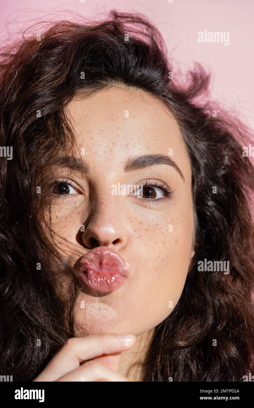 Close up view of freckled woman pouting lips isolated on pink,stock image Stock Photo
