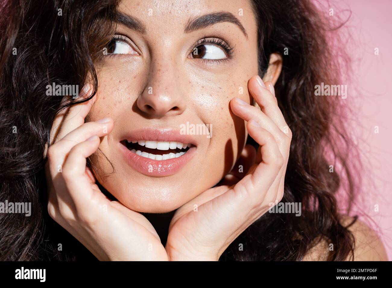 Close up view of dreamy freckled woman looking away isolated on pink,stock image Stock Photo