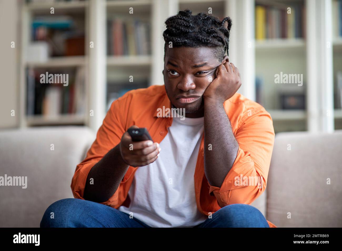 bored african american guy switching channels on tv Stock Photo