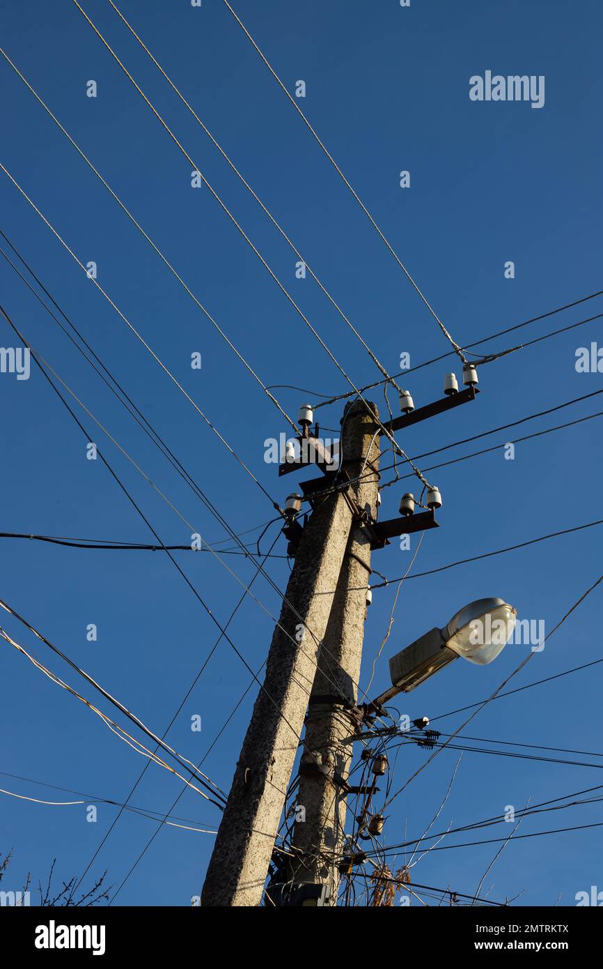 Electric wires hanging on a pole with a lighting lamp photographed from ...