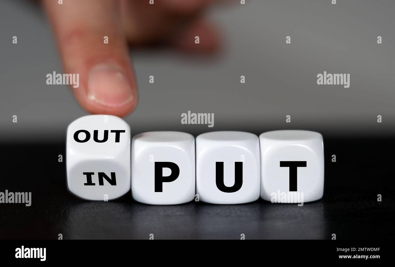 Hand turns dice and changes the word input to output. Stock Photo