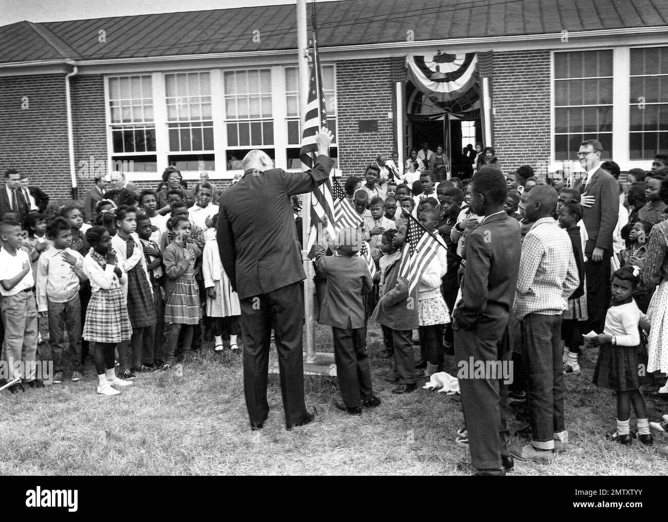 An elementary school student raises the flag at Mary E. Branch No. 2 Free School during opening ceremonies in Farmville, Va., Sept. 16, 1963. The public schools in Prince Edward County have been closed since 1959. At left, Dr. Neil V. Sullivan, superintendent of the Prince Edward Free Schools, watches the proceedings. (AP Photo/Henry Burroughs) Stock Photo