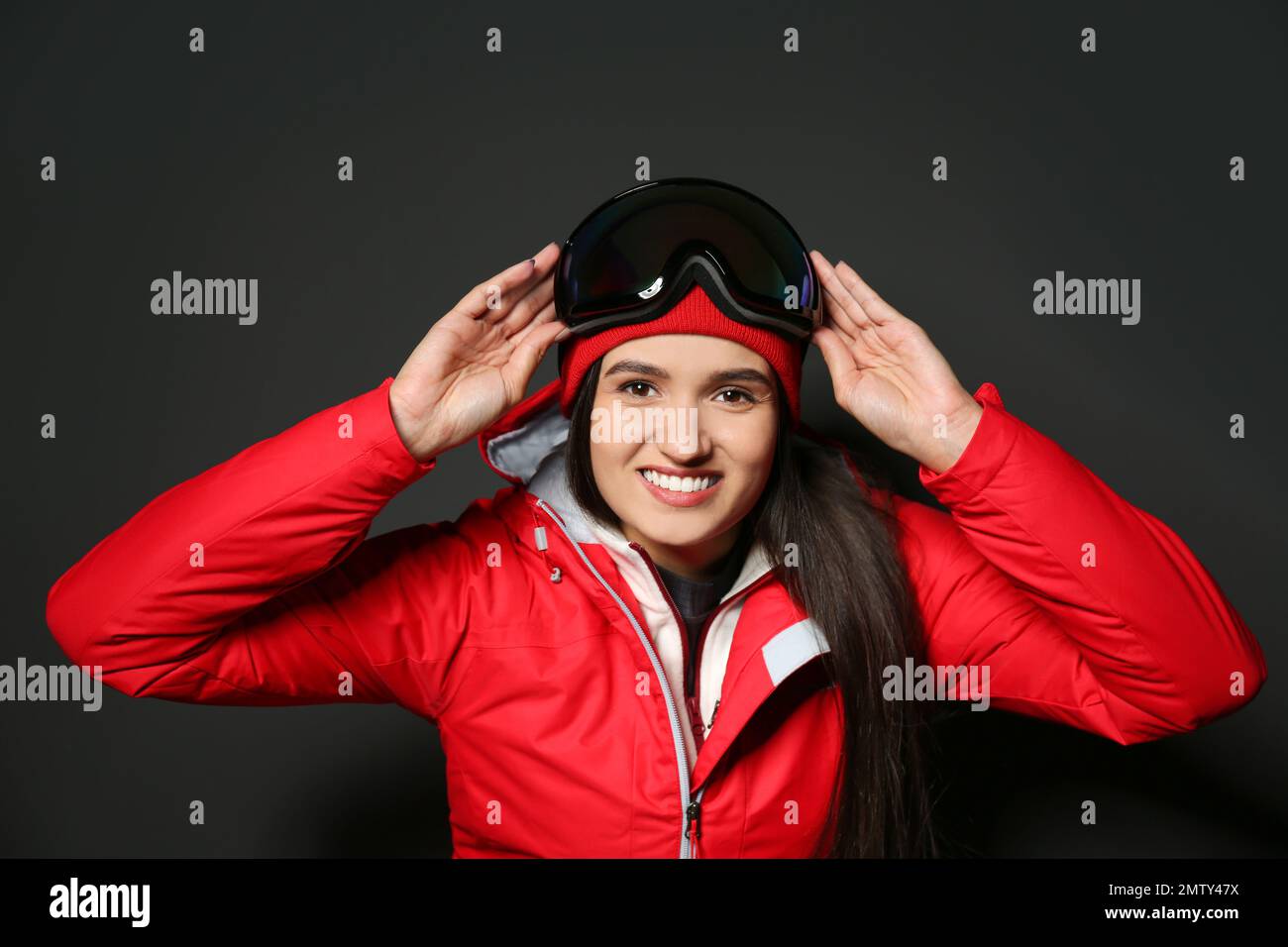 Woman wearing stylish winter sport clothes on black background Stock Photo