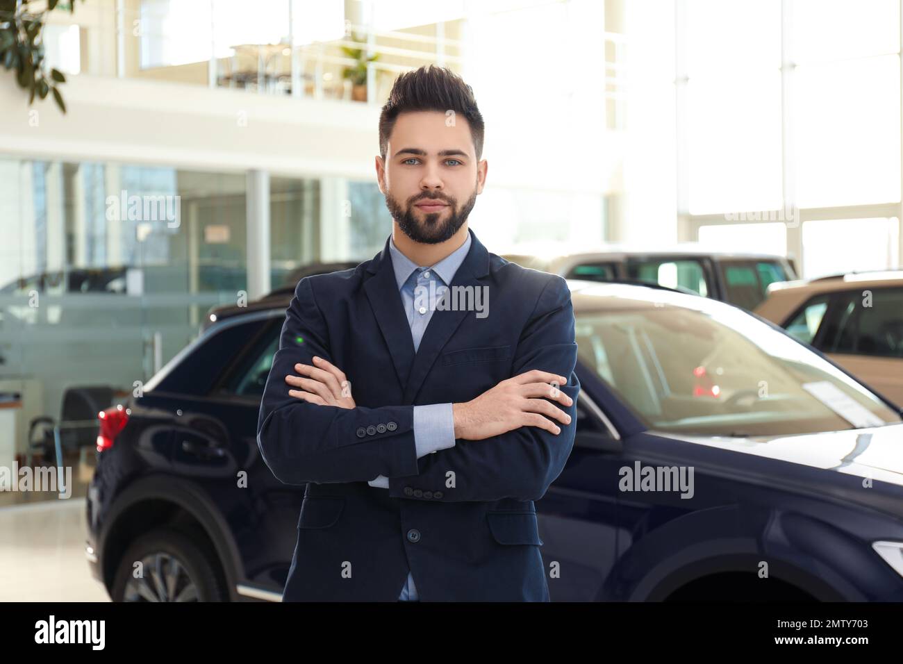 Young salesman near new car in dealership Stock Photo Alamy