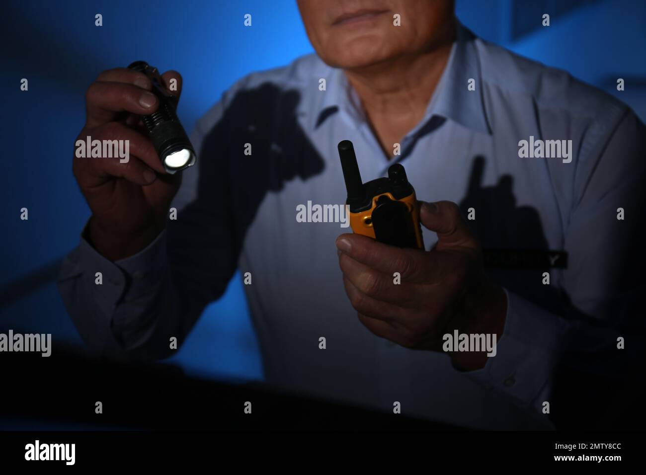 Professional security guard with portable radio set and flashlight in