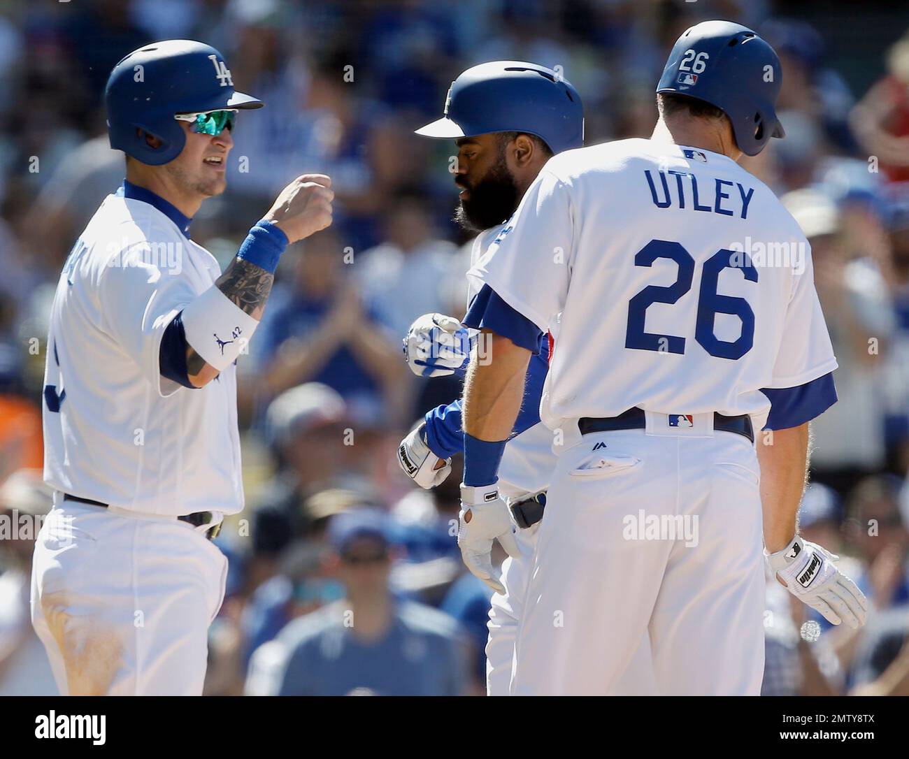 Los Angeles Dodgers' Yasmani Grandal, left, and Chase Utley, right,  congratulate Andrew Toles for hitting a three-run home run against the  Philadelphia Phillies during the sixth inning of a baseball game in
