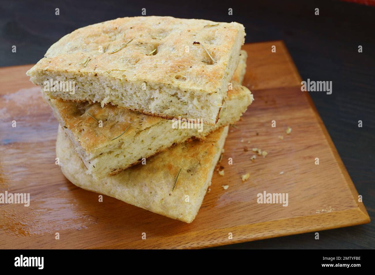 Stack of Rosemary Focaccia Bread Slices on Wooden Breadboard Stock Photo