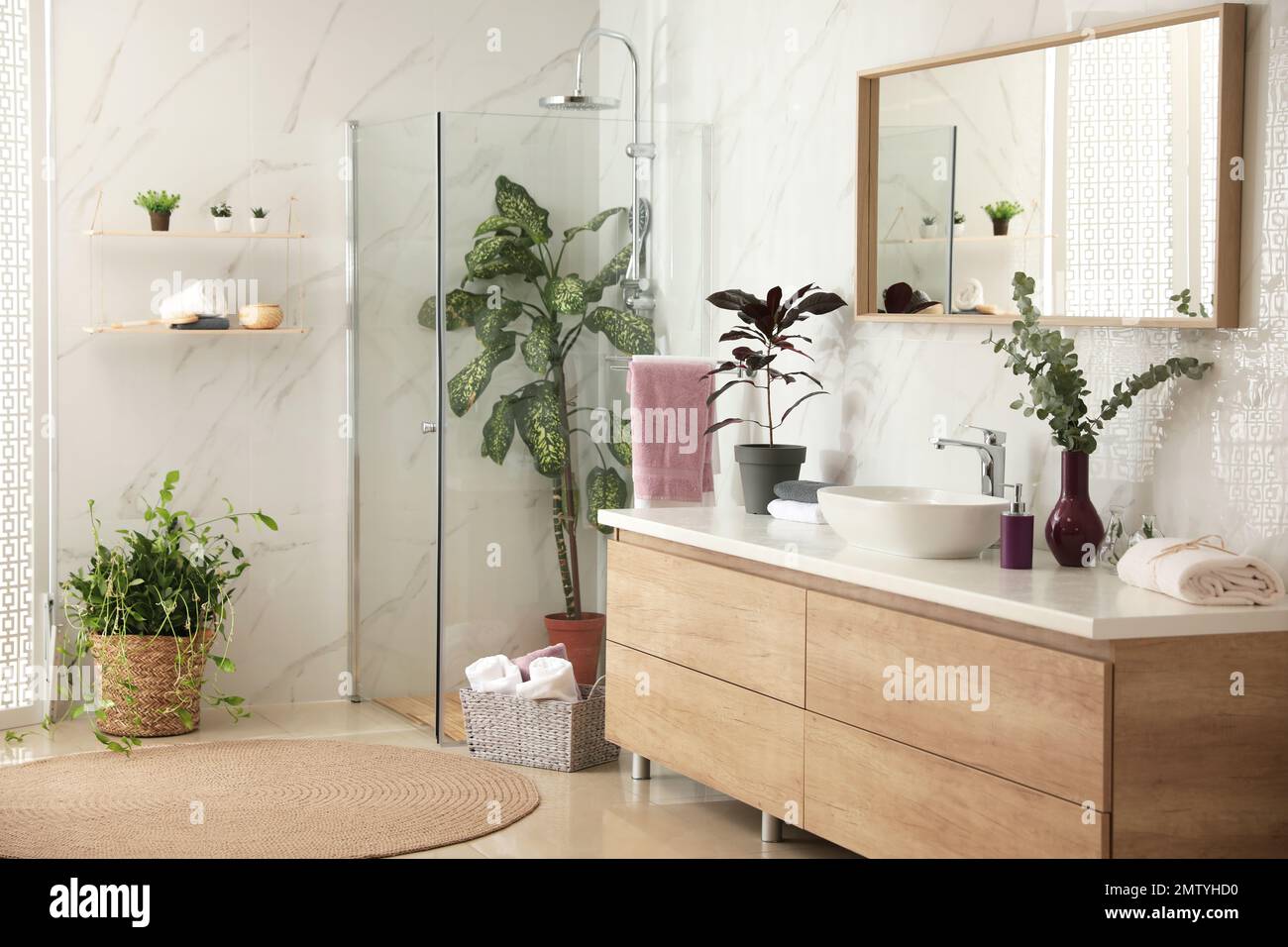 Stylish bathroom interior with countertop, shower stall and houseplants