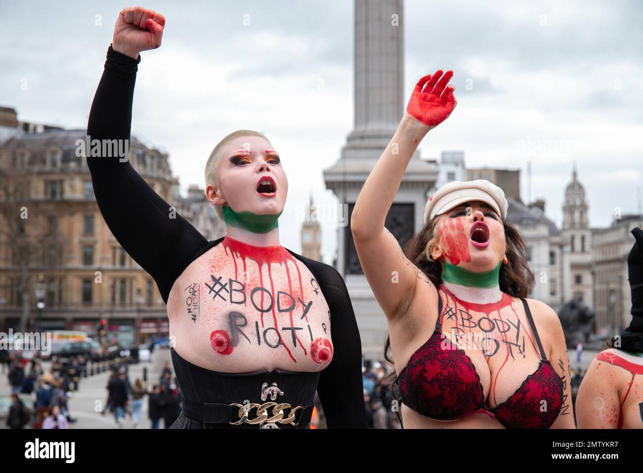 London, England, UK 01/02/2023 Women bare their breasts and bodies for a global Body Riot for Women Life Freedom on No Hijab Day. Women stood on the steps at Trafalgar Square with slogans on their body and symbolically burnt hijabs Stock Photo