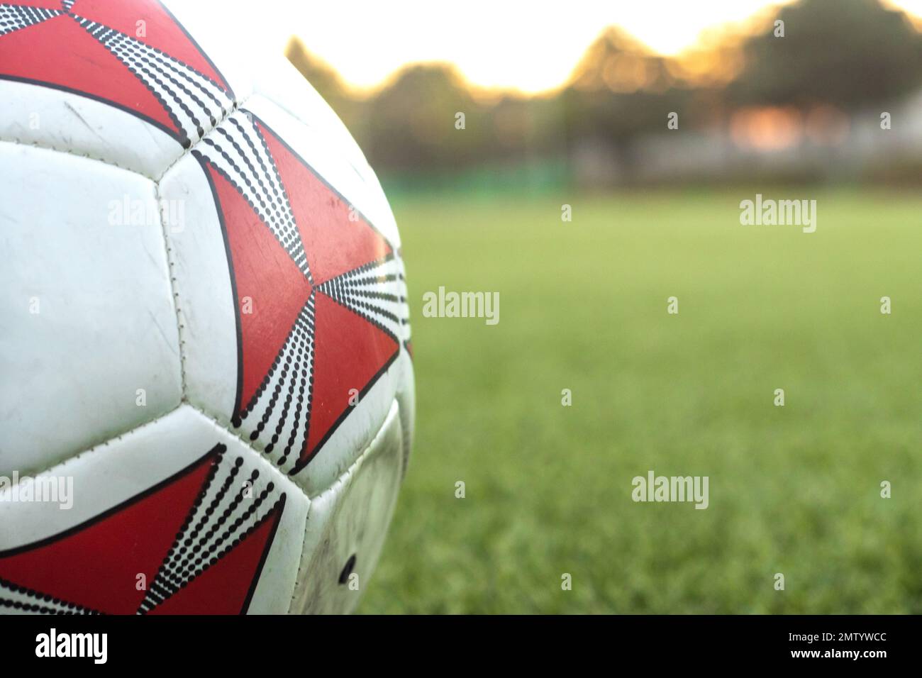 A closeup od white and red soccer ball on the field on blur background