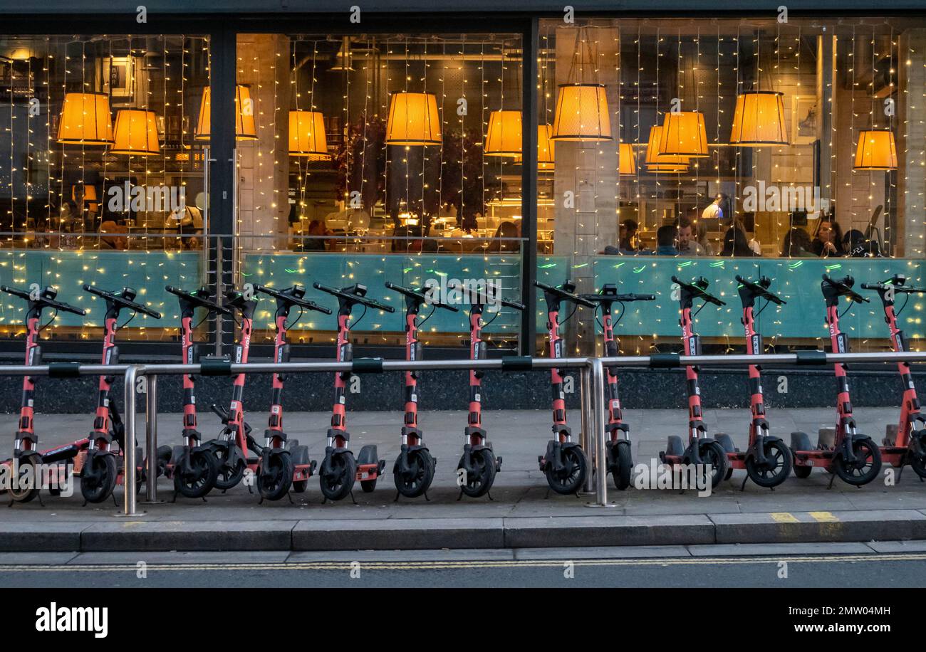 Voi electric rental scooters lined up in front of a restaurant window in Liverpool Stock Photo