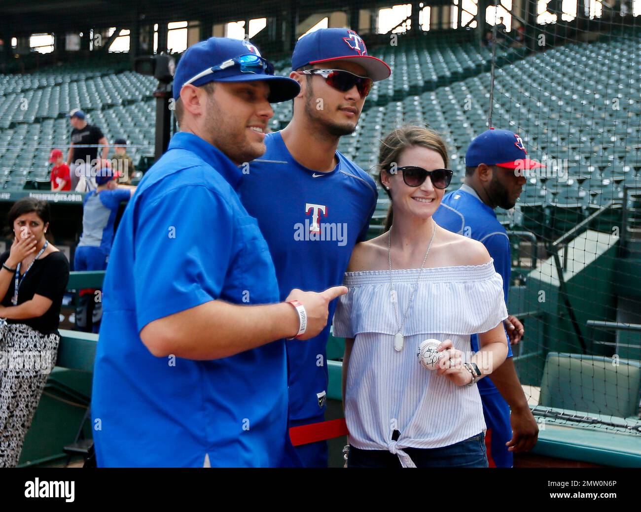 Justin Hall, left, and his wife Alyssa, right, of Aledo, Texas, pose for a  photo with Texas Rangers' Yu Darvish, center, during batting practice  before the Rangers' baseball game against the Minnesota