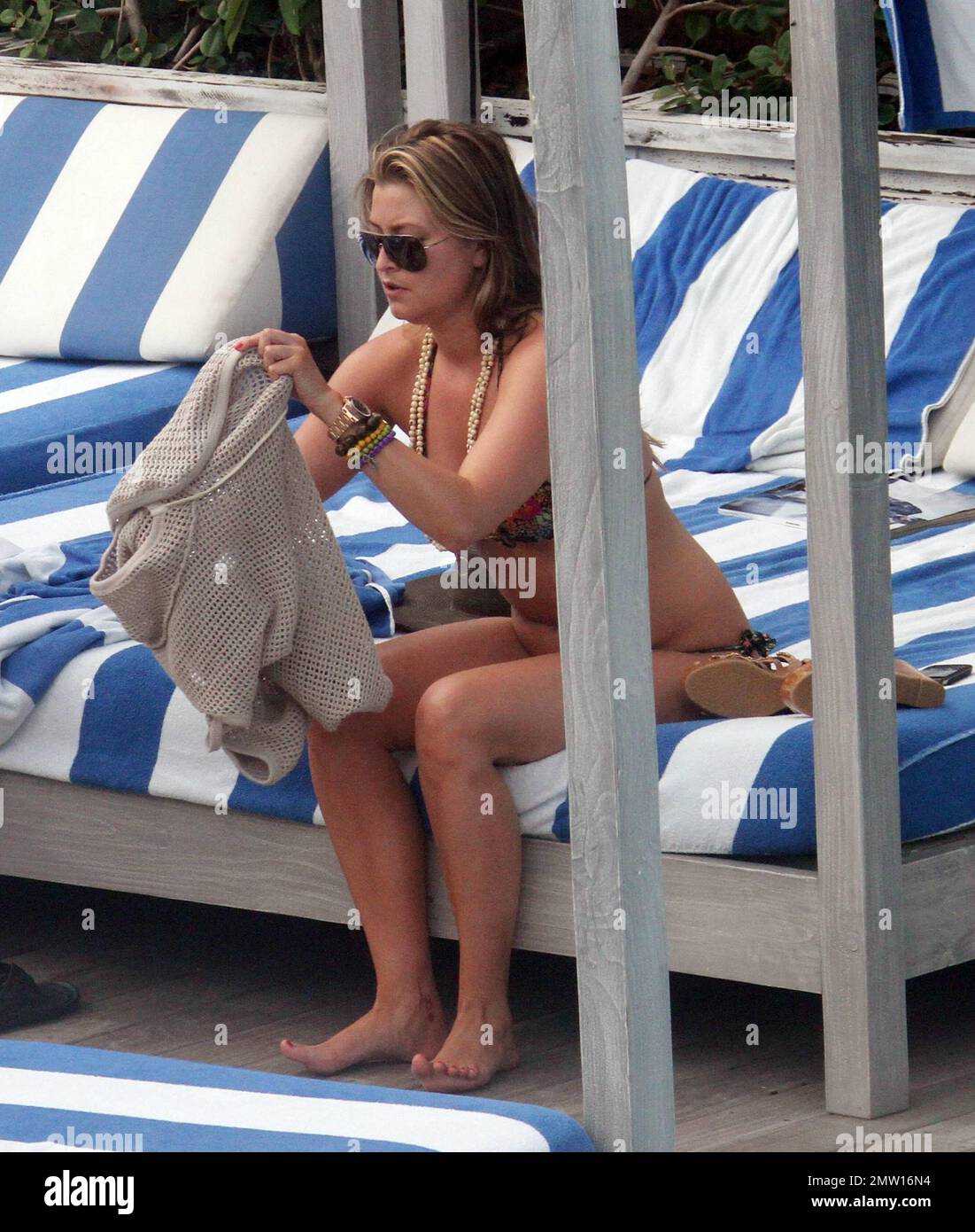 Australian actress and model, Holly Valance, shows off her famous curves in a colorful bikini as she lounged poolside with her boyfriend Nick Candy. The couple, who are suffering from jet lack after an early morning the previous day to watch the Royal Wedding, relaxed in the sun, sipped cold drinks and read magazines. Miami Beach, FL. 4/30/11. Stock Photo