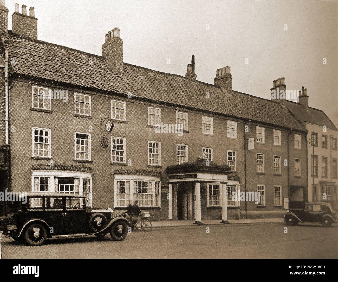 British pubs inns & taverns - A circa 1940 old photograph of the Golden Lion at Northallerton, Yorkshire with two  vintage motor cars of the time parked outsidde. Stock Photo