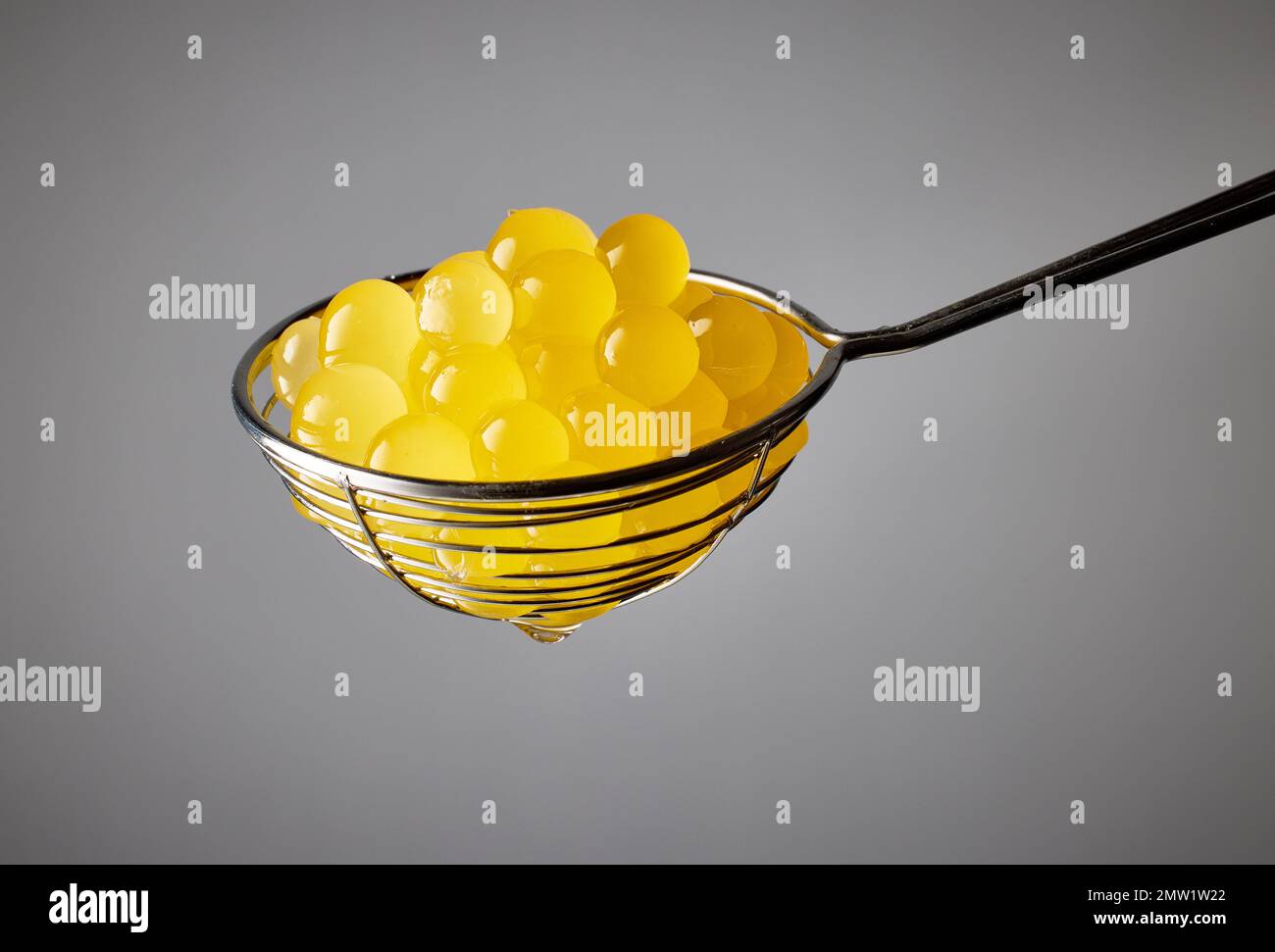 yellow jelly balls for making bubble tea in strainer on grey background