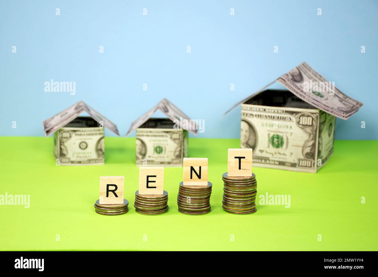 Rent sign in wooden word blocks on stacked quarters with money houses Stock Photo
