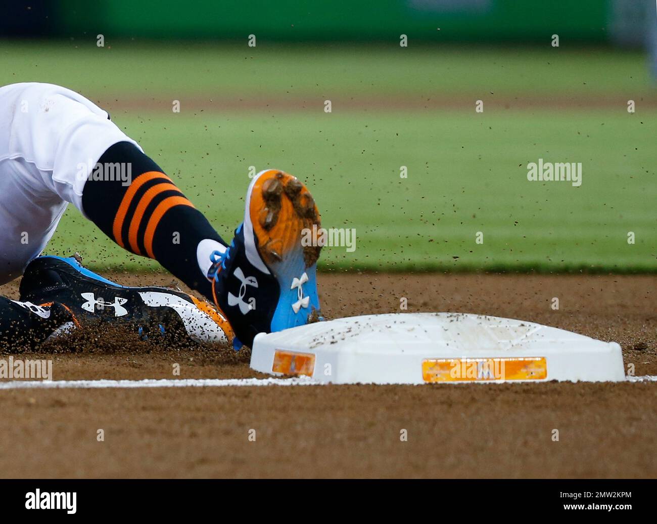 Miami Marlins' Dee Gordon slides in safe at third base on throwing