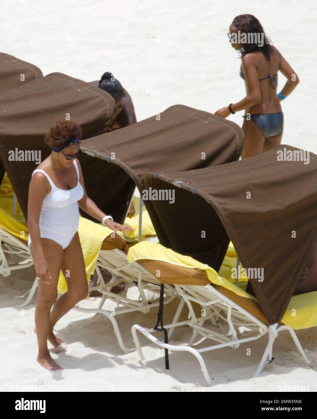 EXCLUSIVE!! R&B singer Whitney Houston, wearing a white swimsuit showing off her fuller figure, enjoys an afternoon at Atlantis Paradise Island beach with 17 year old daughter Bobbi Kristina and friends.   Houston, who turns 47 in two days time on August 9th, enjoyed a hot dog and fizzy drink before taking cover under her towel as she dashed inside her luxury hotel.  Nassau, Bahamas 08/07/2010     . Stock Photo