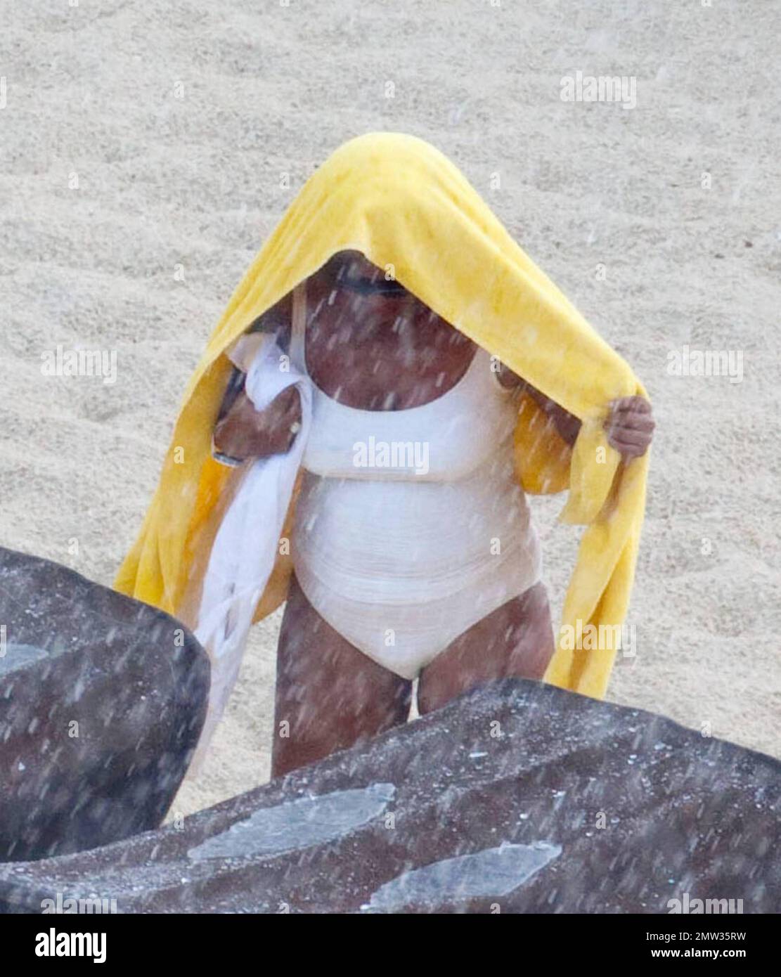 EXCLUSIVE!! R&B singer Whitney Houston, wearing a white swimsuit showing off her fuller figure, enjoys an afternoon at Atlantis Paradise Island beach with 17 year old daughter Bobbi Kristina and friends.   Houston, who turns 47 in two days time on August 9th, enjoyed a hot dog and fizzy drink before taking cover under her towel as she dashed inside her luxury hotel.  Nassau, Bahamas 08/07/2010     . Stock Photo