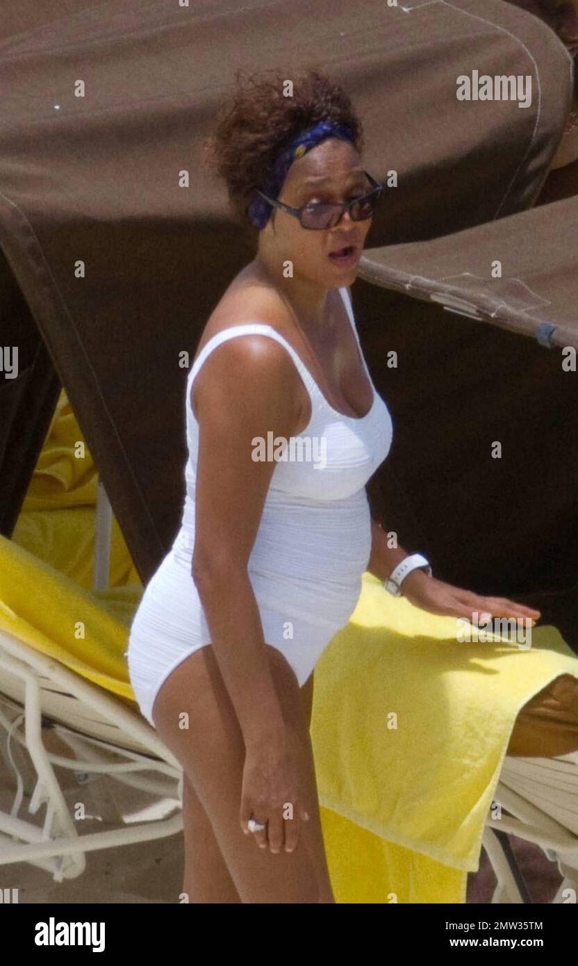 EXCLUSIVE!! R&B singer Whitney Houston, wearing a white swimsuit showing off her fuller figure, enjoys an afternoon at Atlantis Paradise Island beach with 17 year old daughter Bobbi Kristina and friends.   Houston, who turns 47 in two days time on August 9th, enjoyed a hot dog and fizzy drink before taking cover under her towel as she dashed inside her luxury hotel.  Nassau, Bahamas 08/07/2010    . Stock Photo