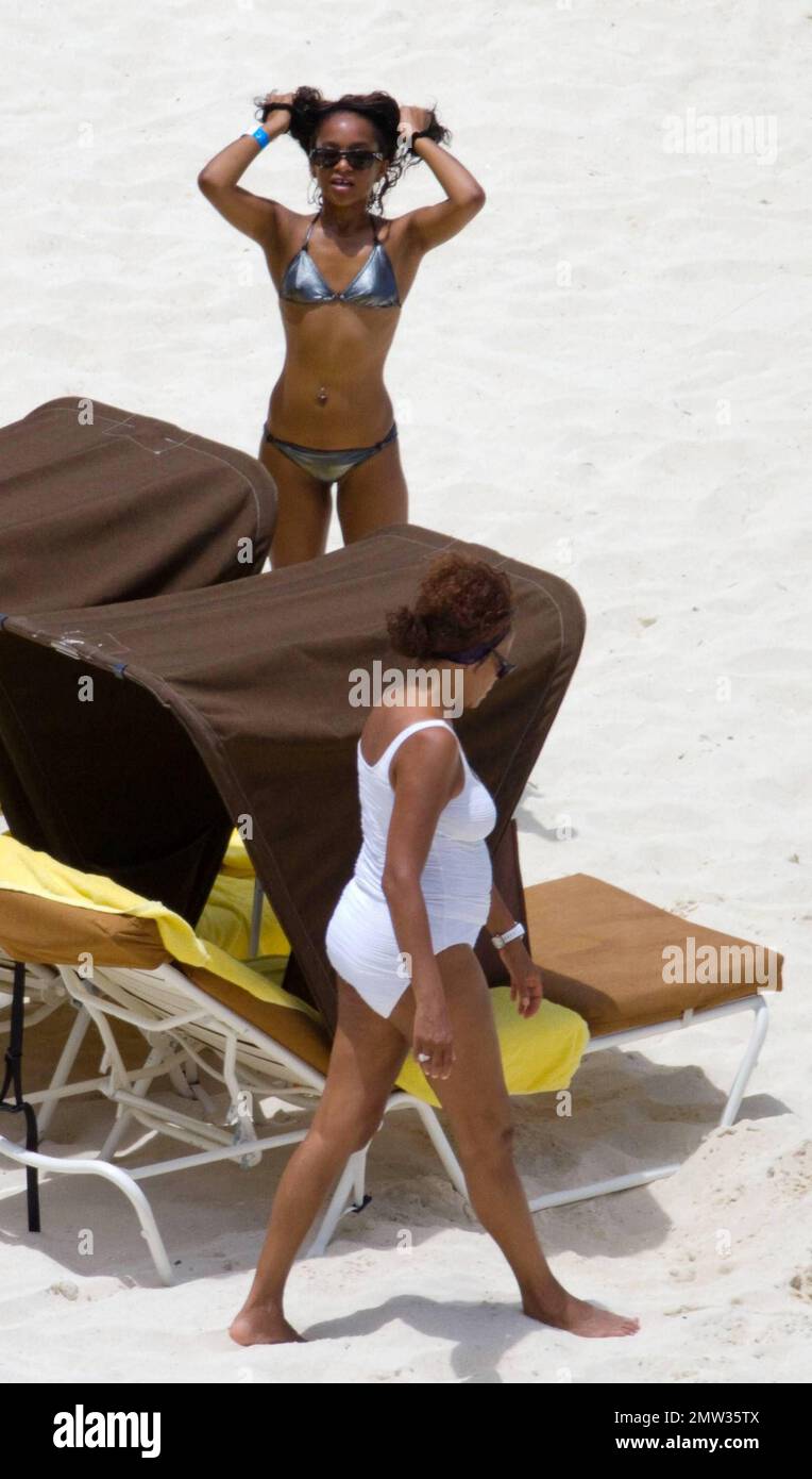 EXCLUSIVE!! R&B singer Whitney Houston, wearing a white swimsuit showing off her fuller figure, enjoys an afternoon at Atlantis Paradise Island beach with 17 year old daughter Bobbi Kristina and friends.   Houston, who turns 47 in two days time on August 9th, enjoyed a hot dog and fizzy drink before taking cover under her towel as she dashed inside her luxury hotel.  Nassau, Bahamas 08/07/2010    . Stock Photo