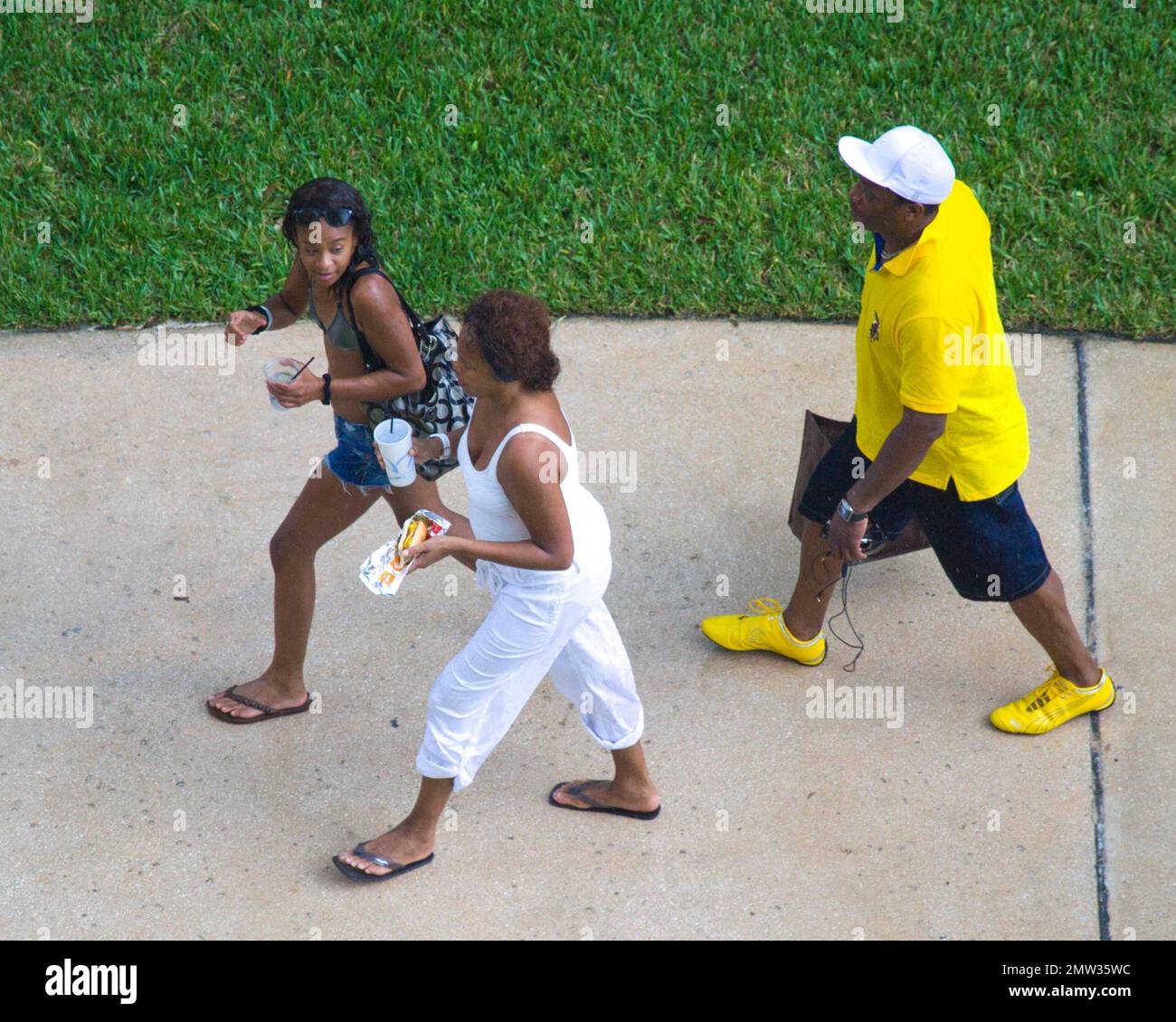 EXCLUSIVE!! R&B singer Whitney Houston, wearing a white swimsuit showing off her fuller figure, enjoys an afternoon at Atlantis Paradise Island beach with 17 year old daughter Bobbi Kristina and friends.   Houston, who turns 47 in two days time on August 9th, enjoyed a hot dog and fizzy drink before taking cover under her towel as she dashed inside her luxury hotel.  Nassau, Bahamas 08/07/2010   . Stock Photo