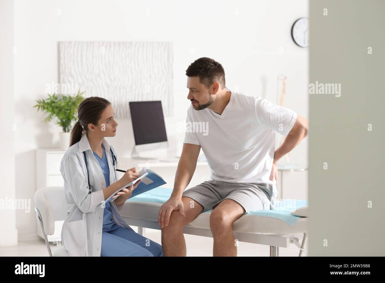 Female orthopedist examining patient with injured back in clinic Stock Photo