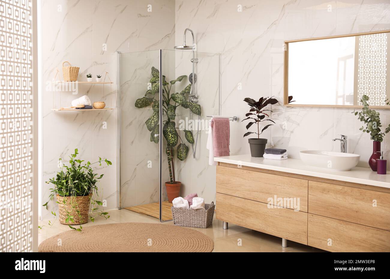 Stylish bathroom interior with countertop, shower stall and houseplants