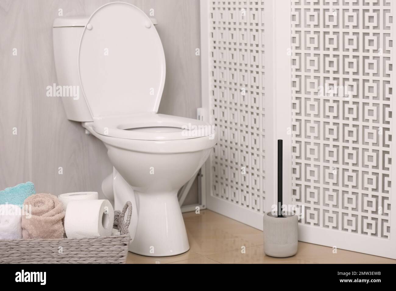 White toilet bowl near folding screen in bathroom Stock Photo Alamy