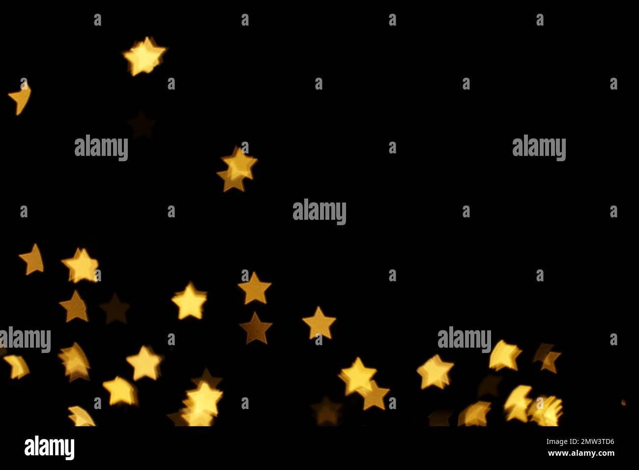 Blurred view of star shaped lights on black background. Bokeh effect Stock Photo