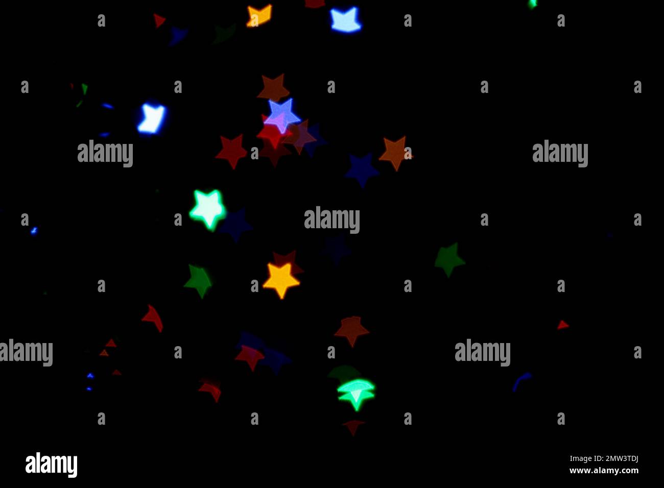 Blurred view of colorful star shaped lights on black background. Bokeh effect Stock Photo
