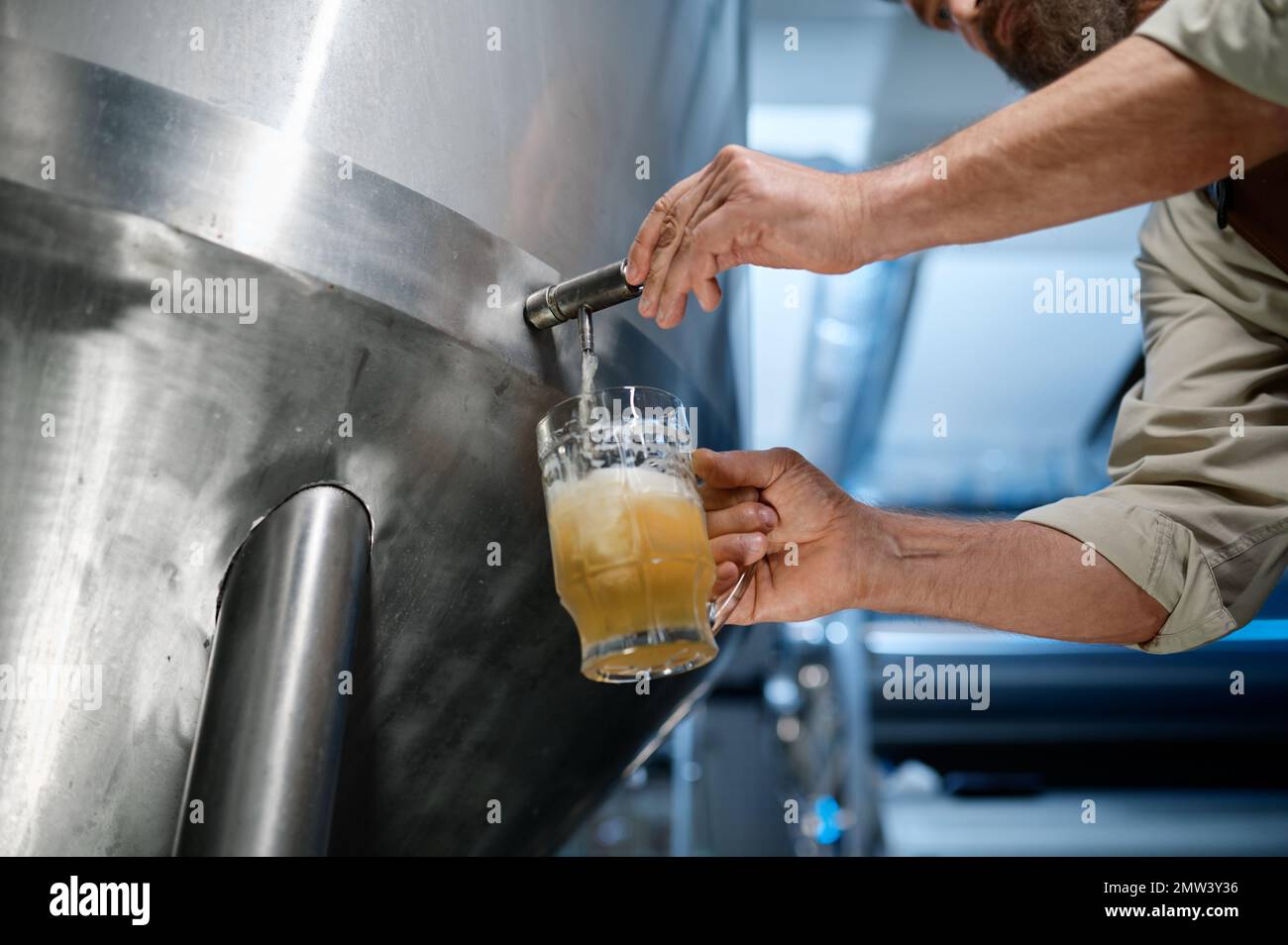 Closeup busy brewery engineer pouring beer to test quality Stock Photo