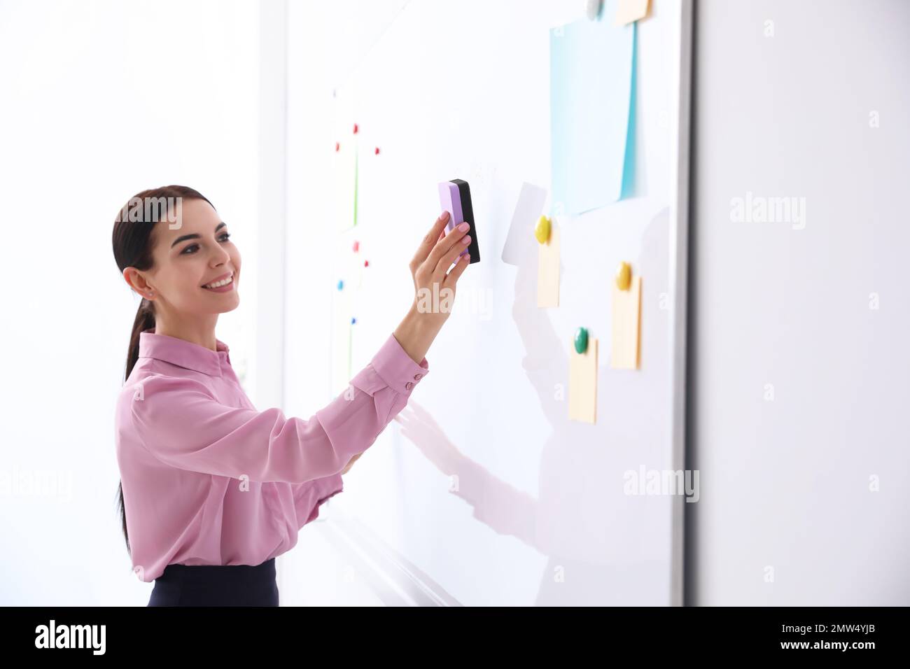 Young teacher cleaning whiteboard in modern classroom Stock Photo Alamy
