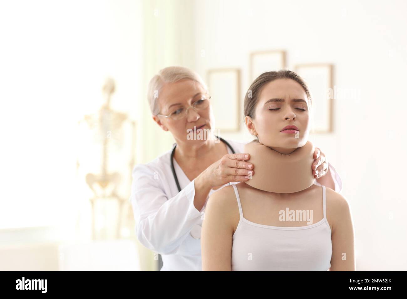 Female orthopedist applying cervical collar onto patient's neck in