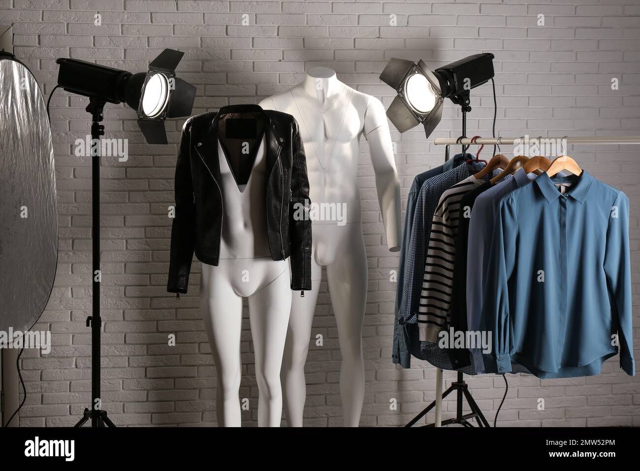 Stylish clothes on ghost mannequin and professional lighting equipment in modern studio. Fashion photography Stock Photo
