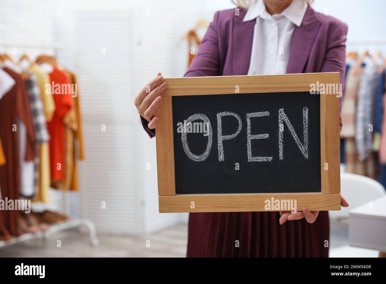 Female business owner holding OPEN sign in boutique, closeup Stock Photo