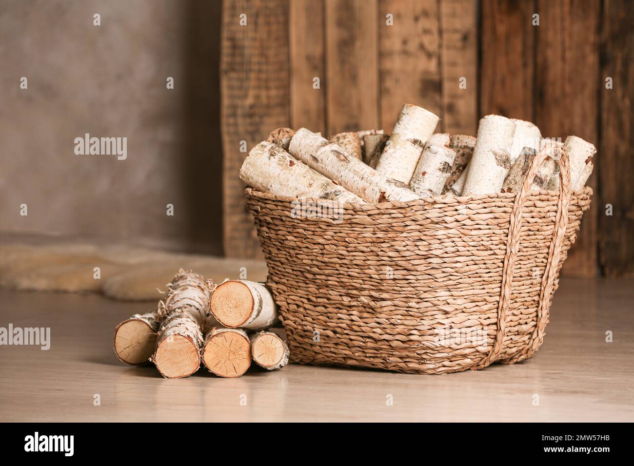 Wicker basket with cut firewood on floor indoors Stock Photo Alamy
