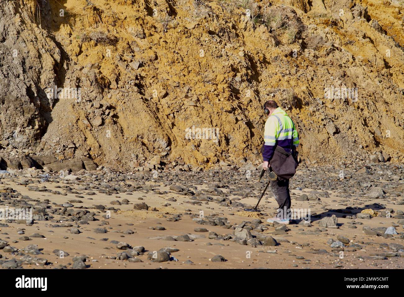 Metal detectorist at The Naze in Essex below the crumbling cliffs Stock Photo Alamy