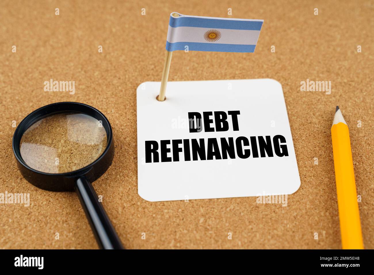 On the table is the flag of Argentina, a pencil, a magnifying glass and a sheet of paper with the inscription - debt refinancing Stock Photo