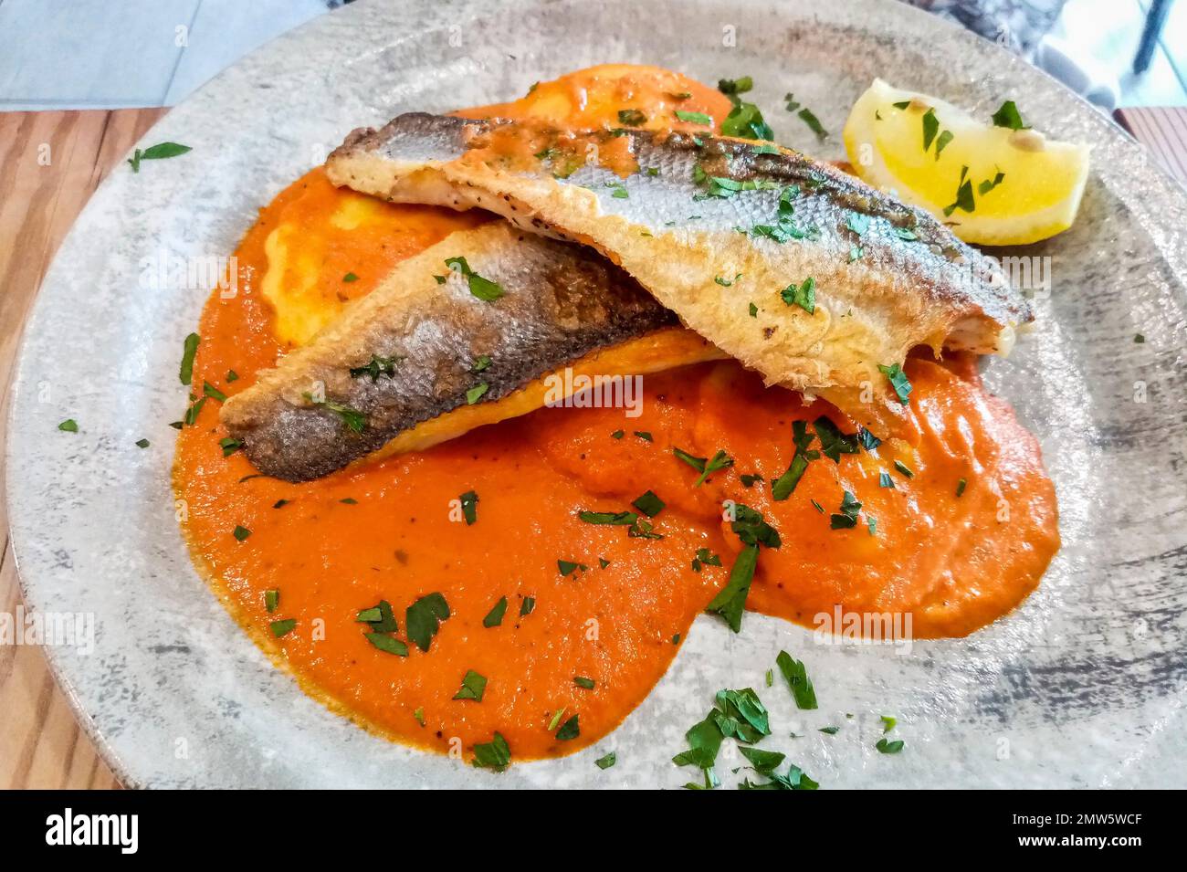 Top view of Italian sea bass dish on tomato sauce. Stock Photo