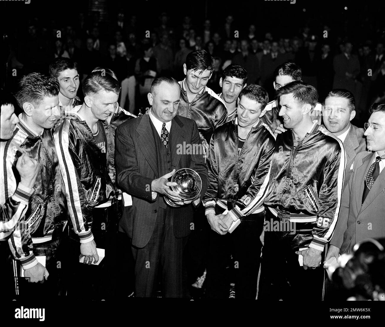 FILE - In this March 26, 1949, file photo, University of Kentucky basketball coach Adolph Rupp and his team admire the NCAA basketball title cup after defeating Oklahoma A&M 46-36 in Seattle. Front row, left to right are: Jim Line, Walter Hirsch, Coach Rupp; Ralph Beard, and Clifford Barker. Star center Alex Groza looks over Rupp's shoulder. The Associated Press is ranking the top 100 college basketball programs of all time using 68 years of data from the AP Top 25 poll. (AP Photo/Paul Wagner, File) Stock Photo