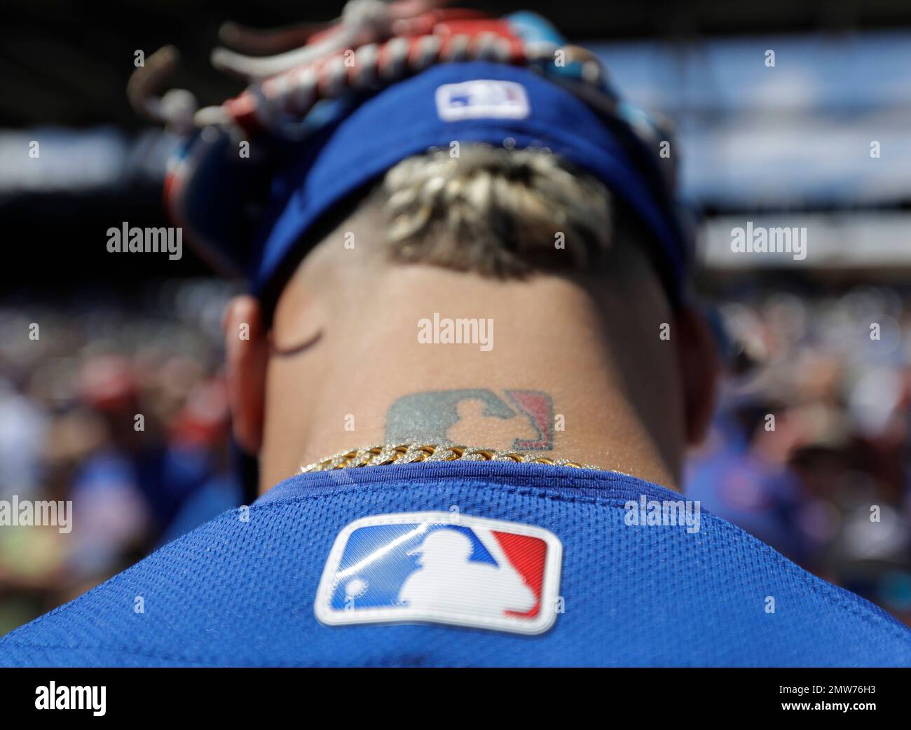The major league baseball logo is tattooed on the back of Chicago Cubs' Javier  Baez neck as he gives autographs before a spring training baseball game  against the Colorado Rockies, Saturday, March